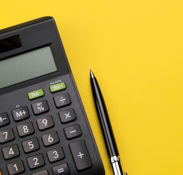 Photo of a calculator and pen on a yellow background.